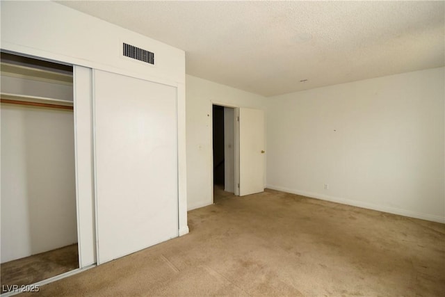 unfurnished bedroom with light carpet, a closet, visible vents, and a textured ceiling