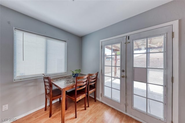 dining room with french doors, light wood-style flooring, and baseboards