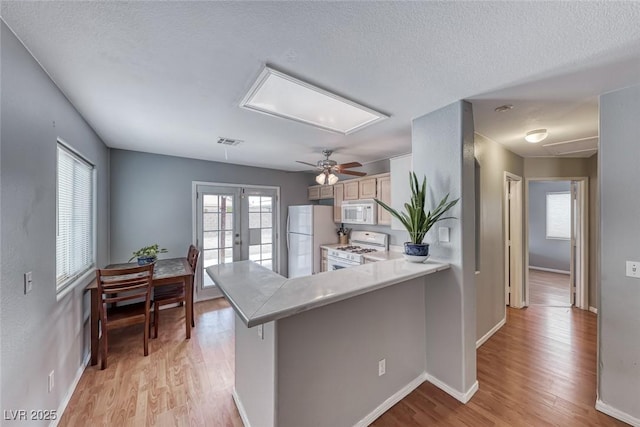 kitchen with french doors, light countertops, visible vents, light wood-type flooring, and white appliances