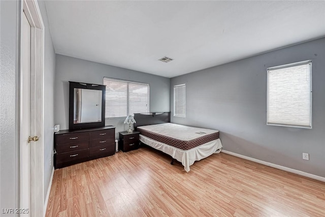 bedroom with baseboards, visible vents, and light wood finished floors