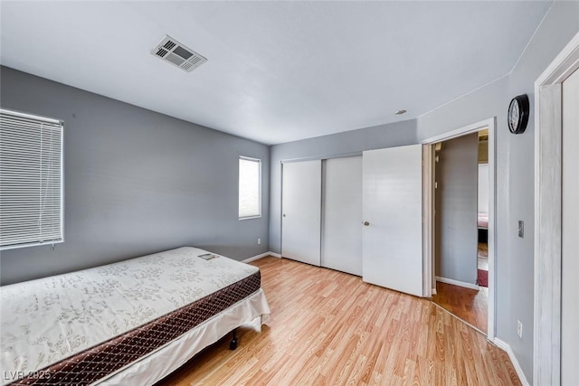 bedroom featuring a closet, visible vents, baseboards, and wood finished floors