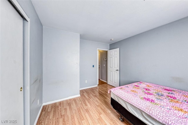 bedroom with a closet, baseboards, and light wood finished floors