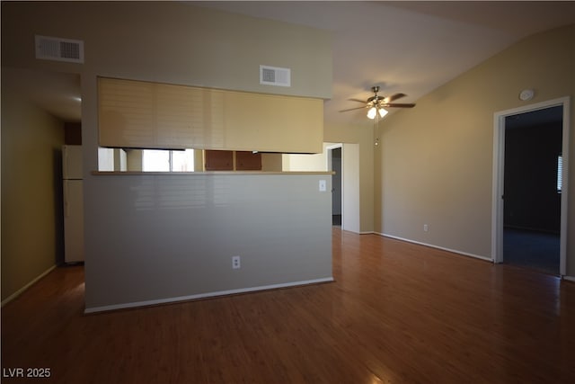 spare room with vaulted ceiling, visible vents, ceiling fan, and wood finished floors