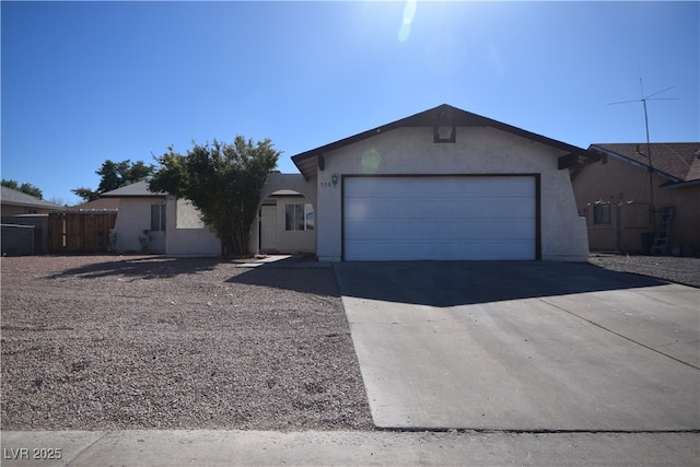 ranch-style home featuring an attached garage, fence, concrete driveway, and stucco siding