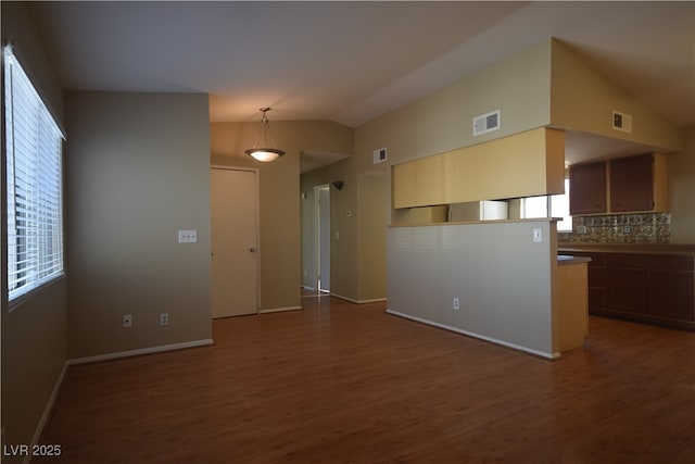 unfurnished room with visible vents, vaulted ceiling, and wood finished floors