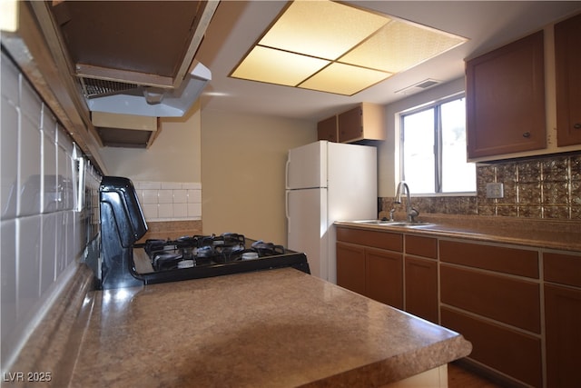 kitchen with visible vents, decorative backsplash, a sink, and freestanding refrigerator