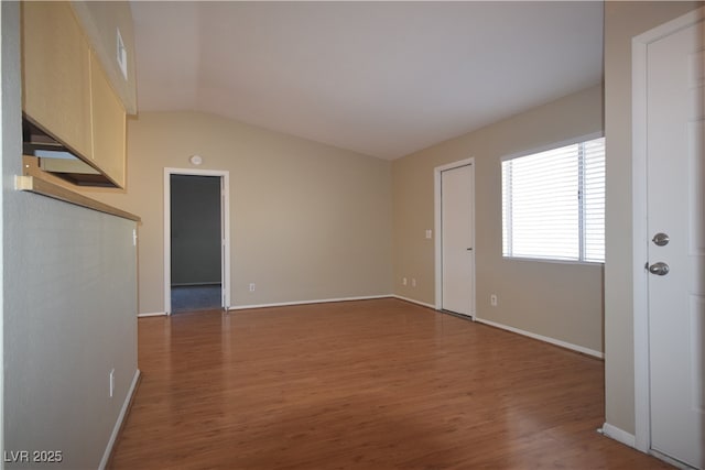 unfurnished room featuring baseboards, vaulted ceiling, and wood finished floors