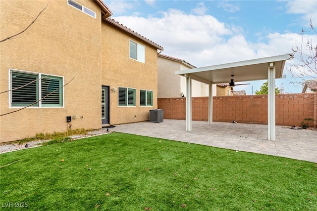 back of property featuring a yard, a patio, stucco siding, central AC, and fence