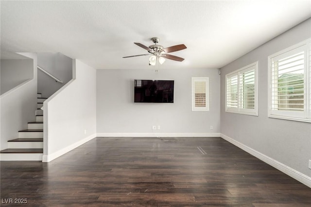 unfurnished living room featuring stairs, ceiling fan, dark wood-style flooring, and baseboards