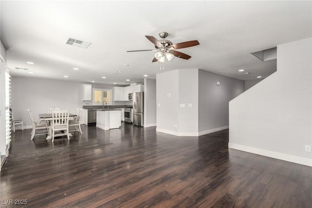 unfurnished living room featuring dark wood-style floors, baseboards, visible vents, and a ceiling fan