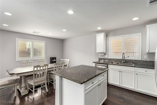 kitchen featuring dark wood finished floors, white cabinets, visible vents, and a sink