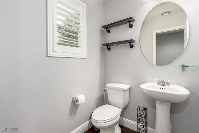 half bathroom with toilet, baseboards, and visible vents