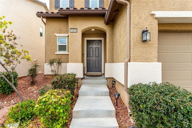 property entrance featuring a garage and stucco siding