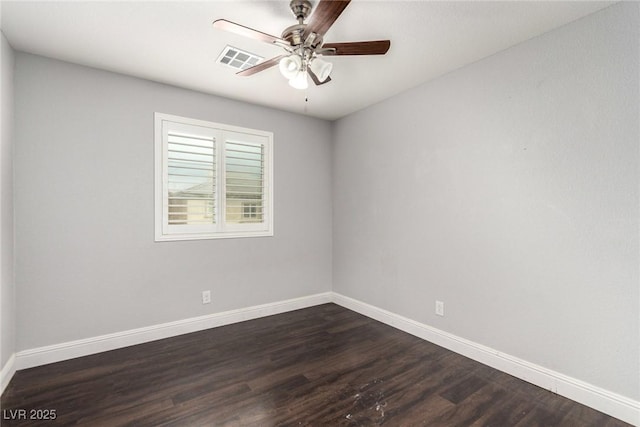 empty room with dark wood-style floors, visible vents, ceiling fan, and baseboards