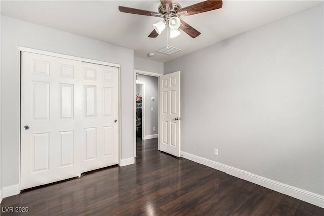 unfurnished bedroom featuring dark wood-style floors, visible vents, baseboards, and a closet