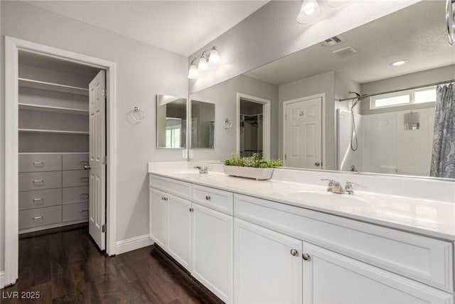 full bathroom with double vanity, visible vents, a sink, and wood finished floors