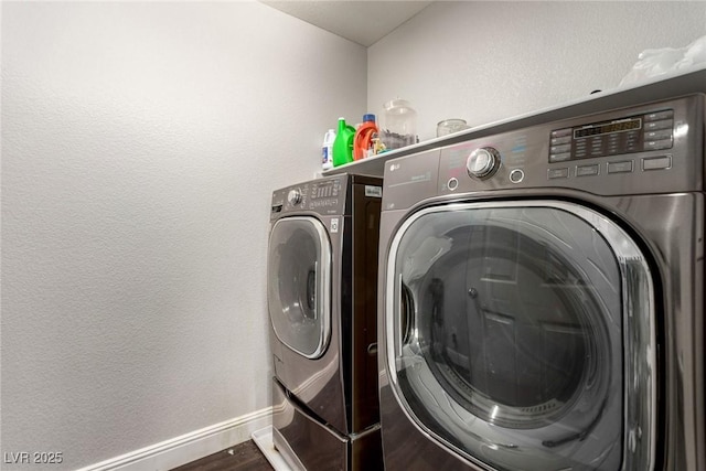 washroom featuring washer and clothes dryer, a textured wall, wood finished floors, laundry area, and baseboards