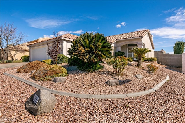 view of front of home featuring an attached garage, a tile roof, fence, and stucco siding