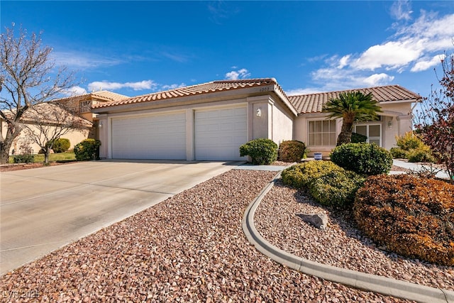 view of front of home featuring a garage, a tile roof, concrete driveway, and stucco siding