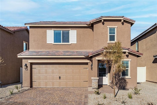 view of front of home with decorative driveway, a tile roof, an attached garage, and stucco siding