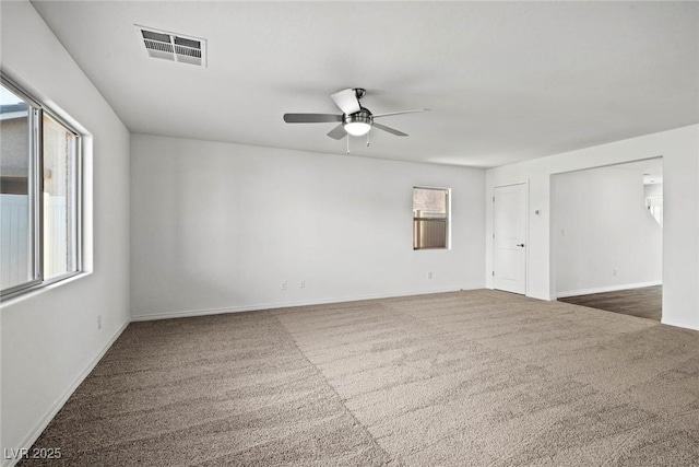 unfurnished room featuring carpet, visible vents, plenty of natural light, and ceiling fan