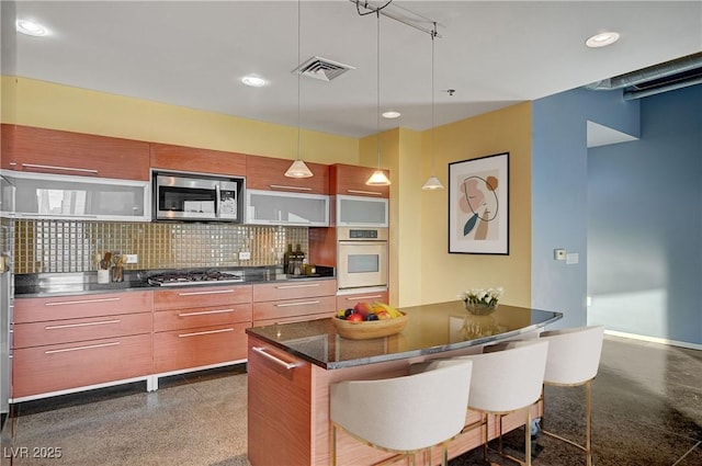 kitchen with visible vents, backsplash, a breakfast bar area, dark speckled floor, and appliances with stainless steel finishes