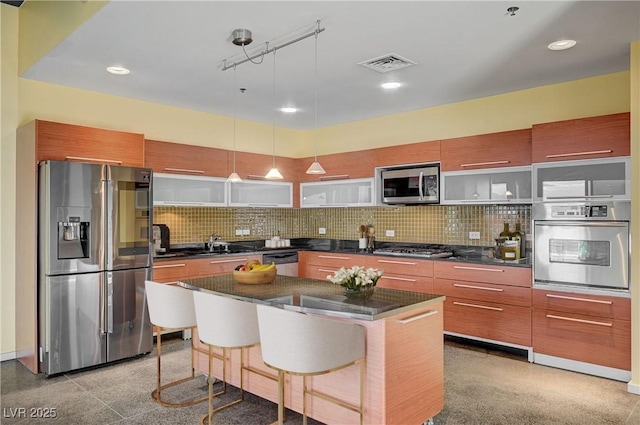 kitchen featuring modern cabinets, backsplash, appliances with stainless steel finishes, and a center island