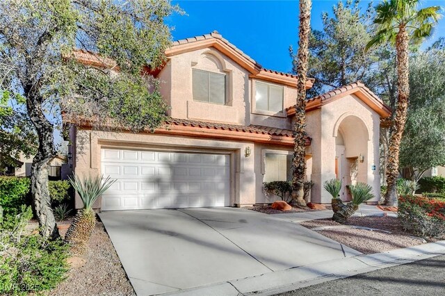 mediterranean / spanish home with stucco siding, a garage, and driveway