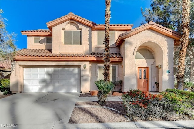 mediterranean / spanish house featuring stucco siding, concrete driveway, an attached garage, and a tile roof