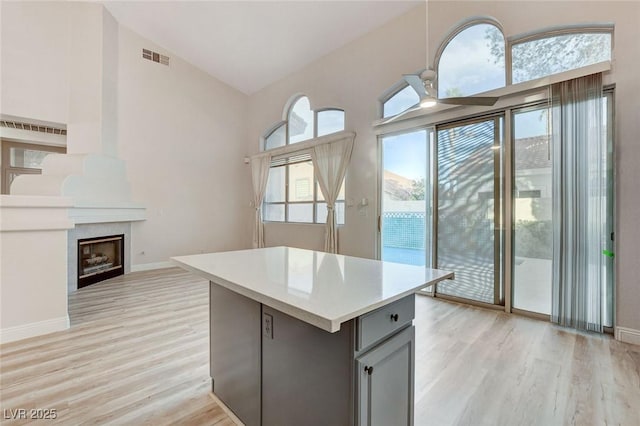 kitchen featuring light wood-style flooring, gray cabinetry, a fireplace, and light countertops