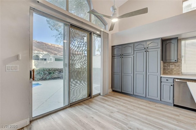 interior space featuring light wood finished floors, baseboards, high vaulted ceiling, and ceiling fan