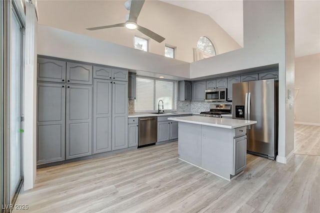 kitchen featuring light wood-type flooring, gray cabinetry, a sink, appliances with stainless steel finishes, and light countertops