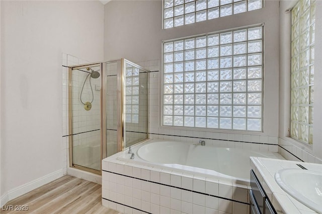 full bathroom featuring vanity, wood finished floors, baseboards, a shower stall, and a bath