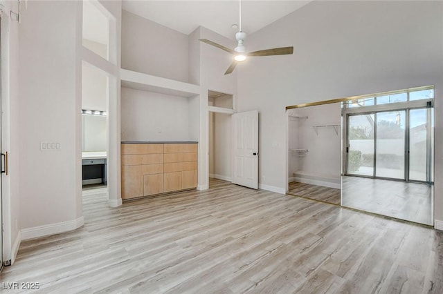 unfurnished bedroom with a closet, high vaulted ceiling, baseboards, and wood finished floors