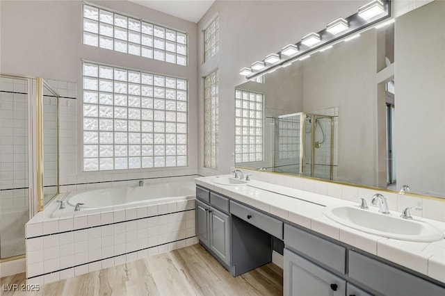 full bathroom with a sink, a garden tub, a stall shower, and double vanity