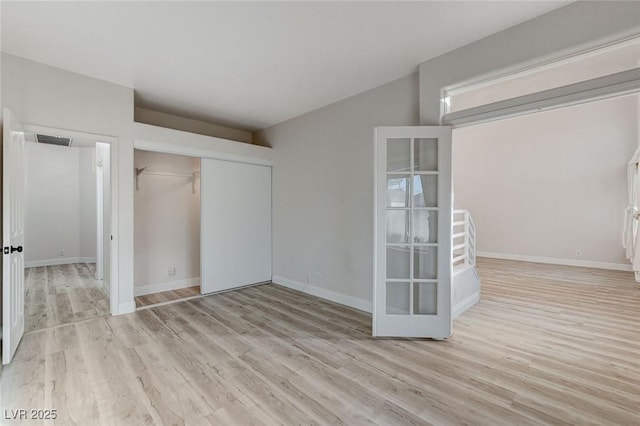 unfurnished bedroom featuring a closet, visible vents, baseboards, and wood finished floors