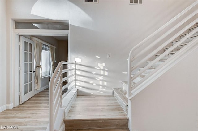 stairs featuring visible vents, baseboards, and wood finished floors