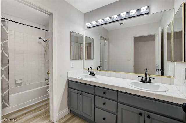 full bathroom featuring double vanity, wood finished floors, shower / bath combo, and a sink