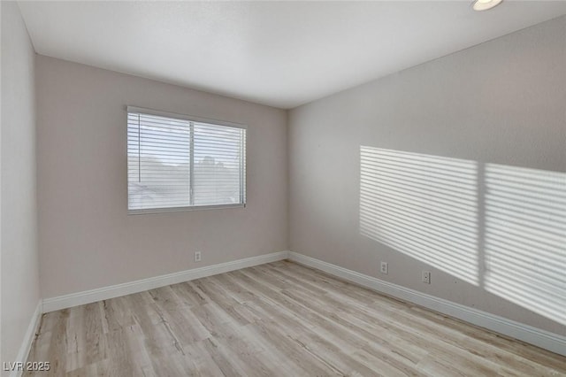 spare room featuring baseboards and light wood-style floors