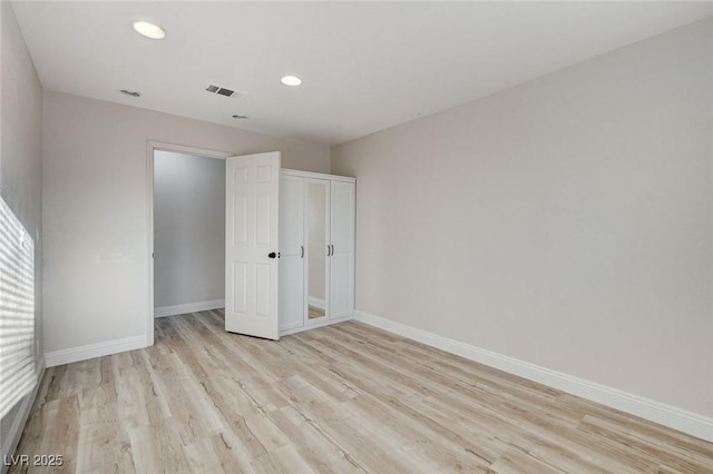 unfurnished bedroom with visible vents, baseboards, recessed lighting, light wood-style floors, and a closet