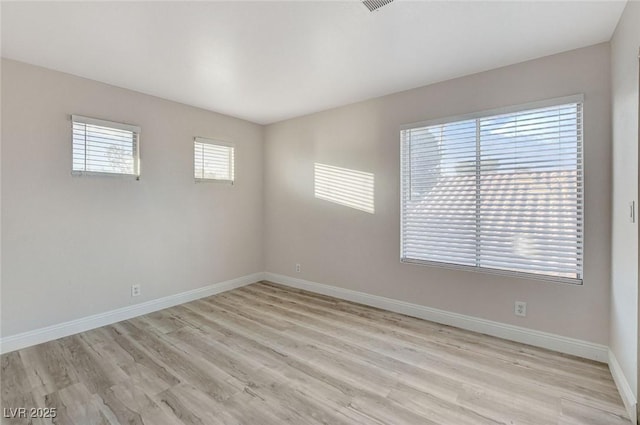 spare room featuring visible vents, baseboards, and light wood-style flooring