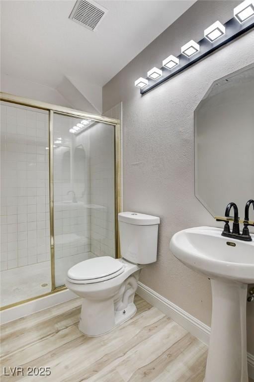 bathroom featuring toilet, wood finished floors, visible vents, and a stall shower