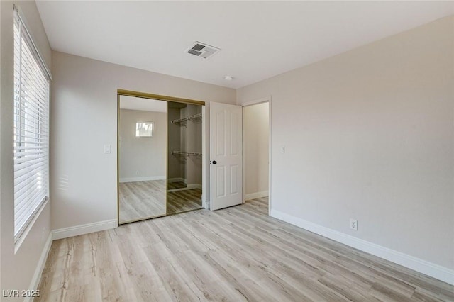 unfurnished bedroom with light wood-style floors, visible vents, a closet, and baseboards