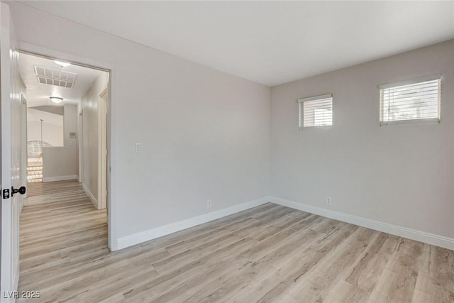 unfurnished room featuring visible vents, light wood-style flooring, and baseboards