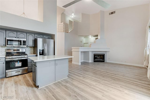 kitchen with visible vents, gray cabinetry, light countertops, light wood-style floors, and appliances with stainless steel finishes