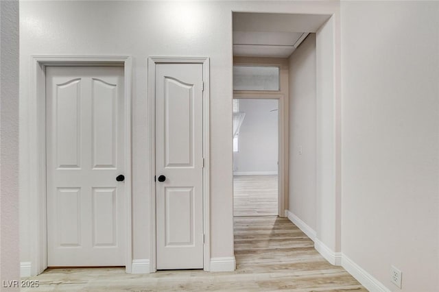 interior space featuring baseboards and light wood finished floors