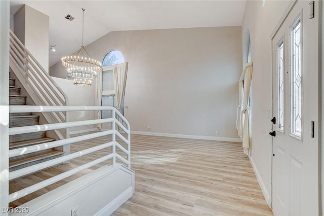 entryway featuring a chandelier, stairway, a healthy amount of sunlight, and lofted ceiling