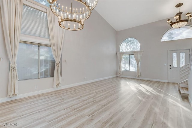 foyer entrance with a notable chandelier, high vaulted ceiling, baseboards, and wood finished floors