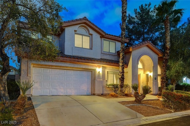 view of front of home featuring stucco siding, a tiled roof, concrete driveway, and a garage