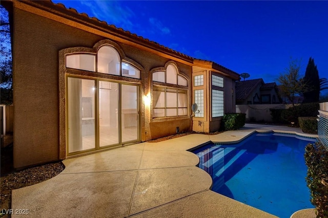 pool at night with a fenced in pool and a patio